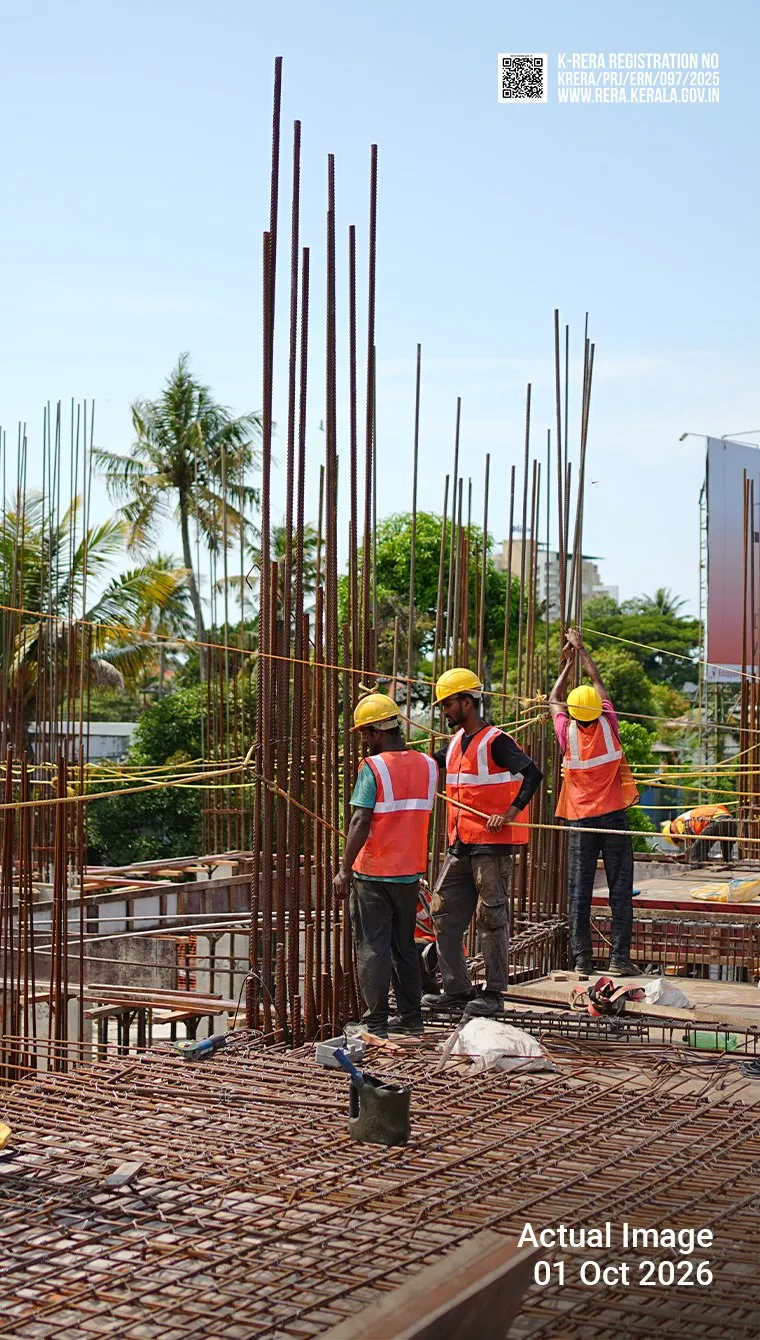 Flora construction site on 1 October 2026: three workers in safety gear on the slab among column reinforcement